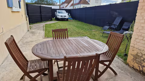 Le jardin clos de Dolce Vita : table en bois, chaises et transats sur la pelouse
